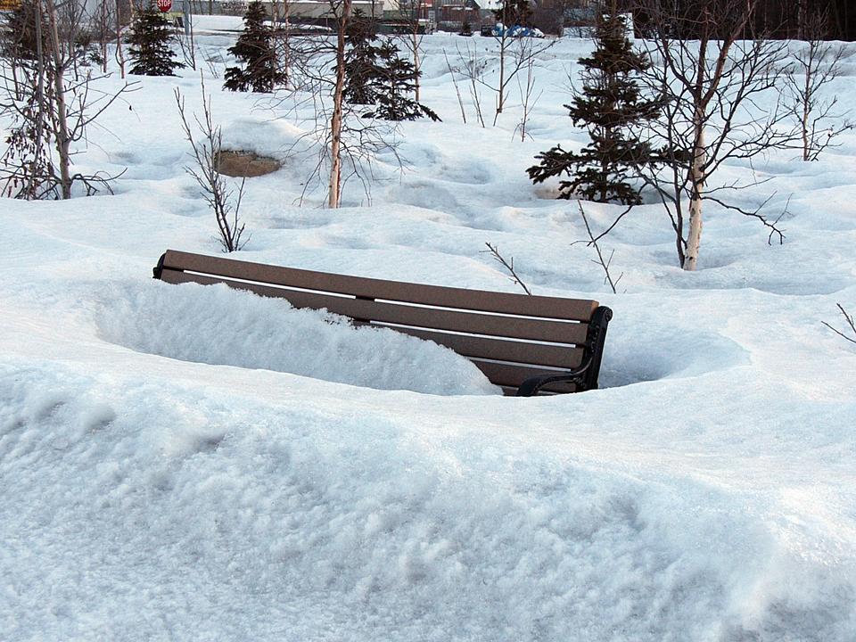 Bus stop bench emerges from the slowly melting snow